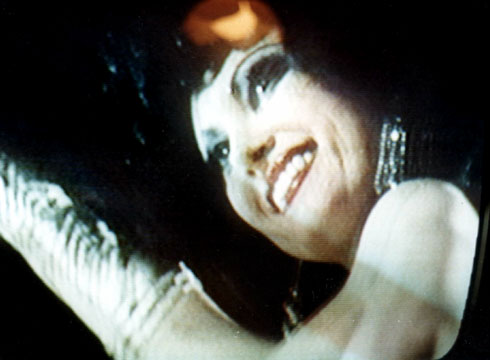 Close up screen capture of sexy, pearl skinned stripper Kellie Everts perfoming on stage